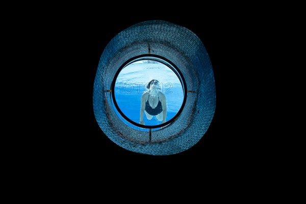 Woman Swimming in the Ship Porthole in Underwater in Swimming Pool in a Sunny Day in Switzerland