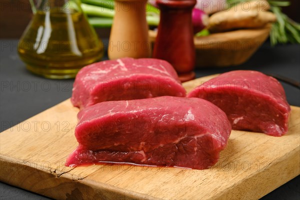 Closeup view of uncooked steaks on wooden cutting board