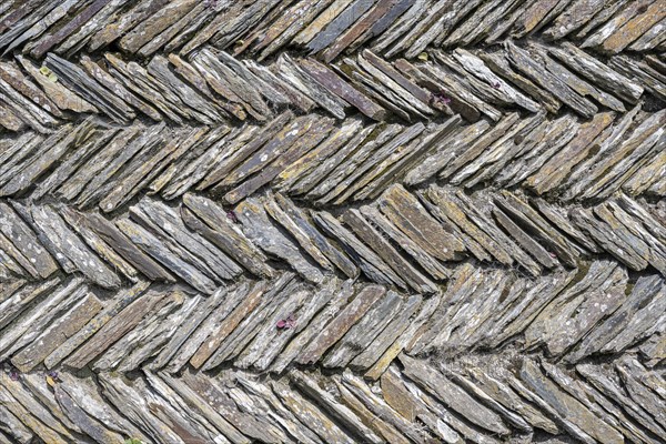 Slate slabs stacked in a herringbone pattern to form a wall