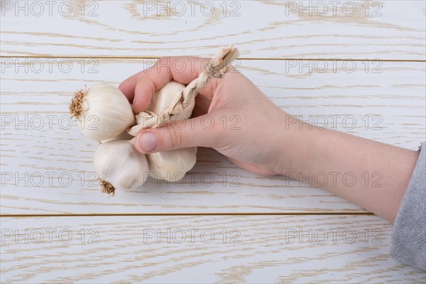 Hand holding cloves of garlic on a wooden texture