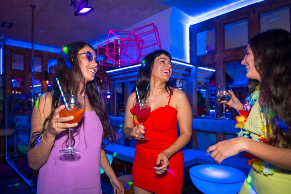 Portrait attractive women in a nightclub dancing with the glasses at a summer night party in a pub