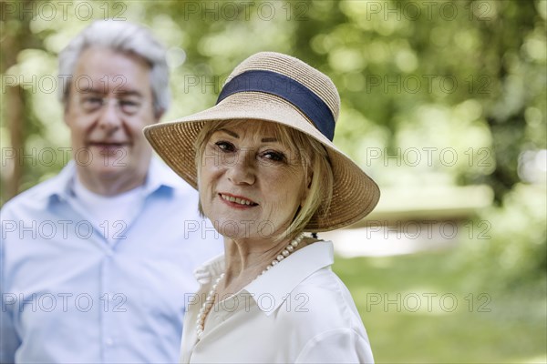 Summery dressed older woman together with her grey-haired man in the park