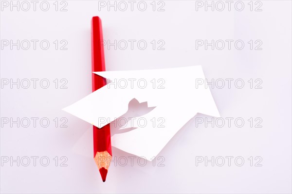 Color pencil near a paper house on a white background