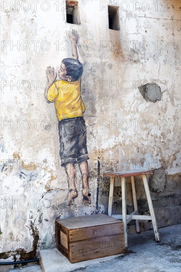 Street art Reaching Up on a wall in George Town on Penang Island