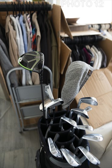 Moving House with Cardboard Boxes and Clothes and Golf Bag with Golf Clubs in Living Room in Switzerland