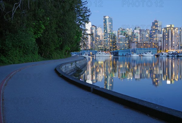 Illuminated skyscrapers and pleasure boats reflected in the calm water