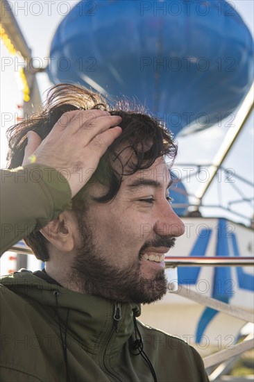 Very excited emotional portrait of a young latin man in the cabin of a ferris wheel. Amusement park adventures and fear of heights