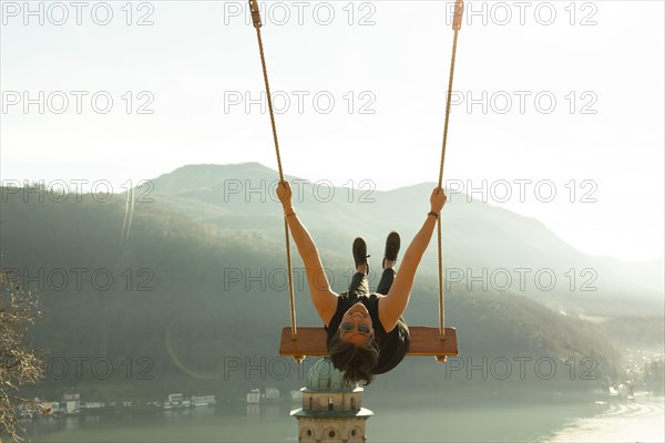 Woman on a Swing with Mountain View and Sunlight over Lake Lugano in Morcote