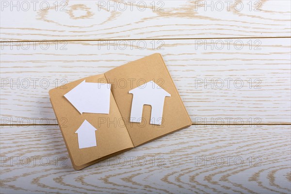 Little paper house on a notebook on parquet