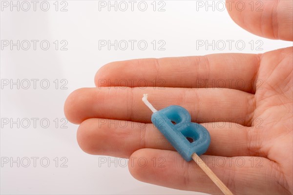 Color candle in hand on sticks writes the letter B