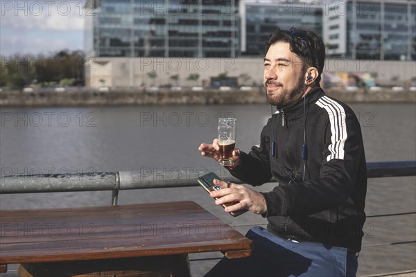 Latin tourist drinking beer and listening music at an outdoor bar in Puerto Madero