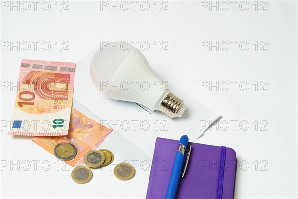 Light bulb on an electricity bill and banknotes and coins on a white background.concept of electricity price increase