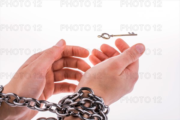 Both chained hands and the key on white background