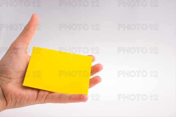 Hand holding yellow color rectangular paper on a white background