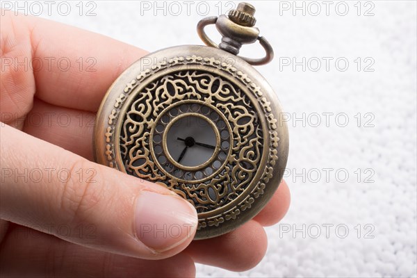 Retro style pocket watch in hand on white background