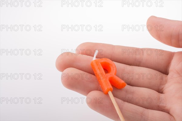 Color candle in hand on sticks writes the letter R