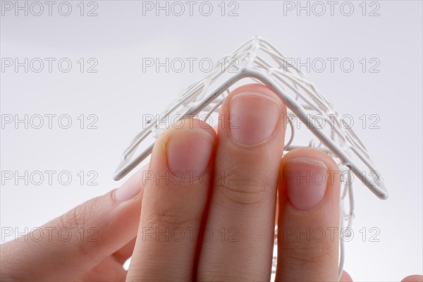 Little model house made of white metal wire in hand