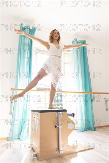 Woman Exercising on Pilates Machine Against a Window With Sunlight