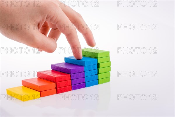 Hand playing with colored domino on white background