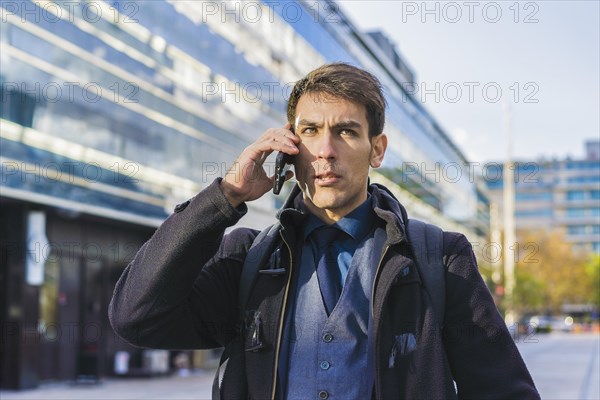 A handsome businessman talking on the cell phone near his office. Copy space