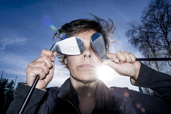 Golfer Holding Her Golf Clubs in Front of Her Eyes with Sunlight