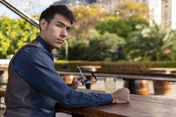 Businessman sitting at an outdoor bar drinking lemonade