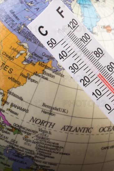 Hand placing a thermometer on a little model globe