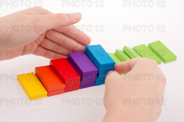 Hand playing with colored domino on white background