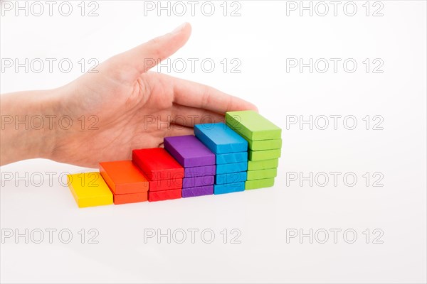 Hand playing with colored domino on white background