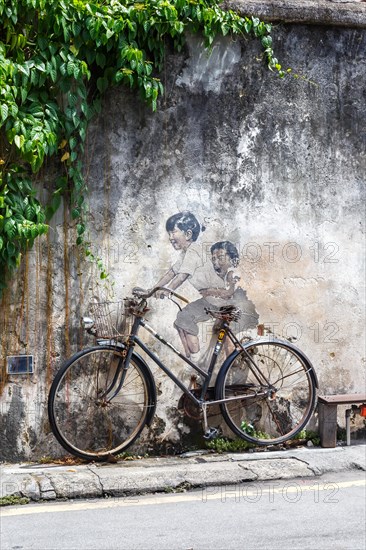 Street art boy and girl on bicycle on a wall in George Town on Penang Island