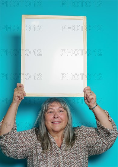 Older white-haired woman holding a white board to paste text on