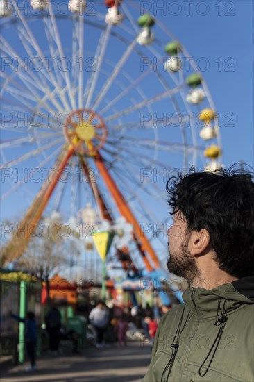 Portrait of latino man in an amusement park posing happy with the ferris wheel in the background