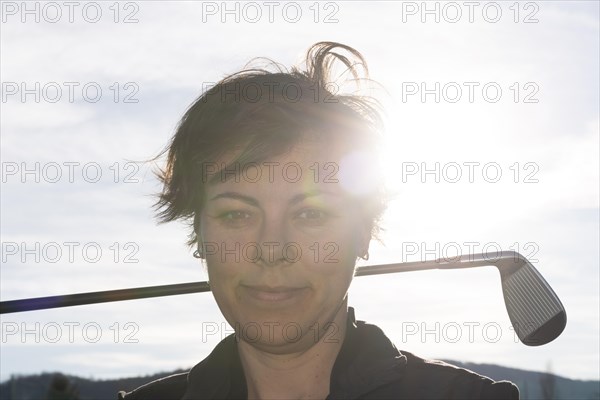 Golfer Leaning Her Golf Club on Her Shoulders with Sunlight