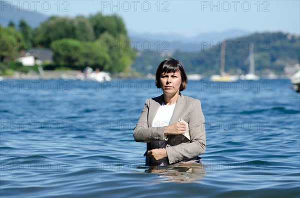 Elegant Business Woman with Suit Standing in the Water and Holding a Newspaper