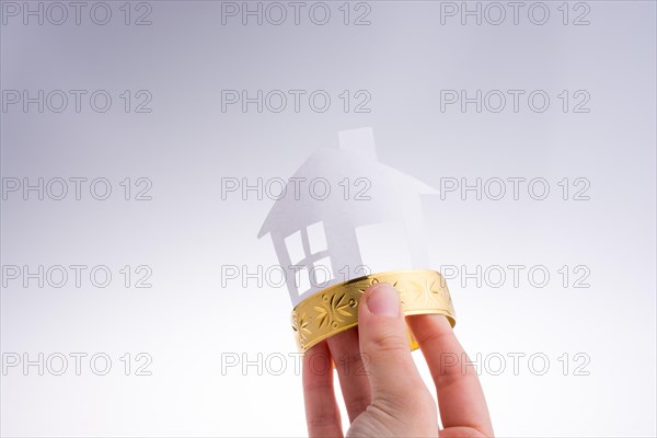 Paper house with a golden bracelet on a white background