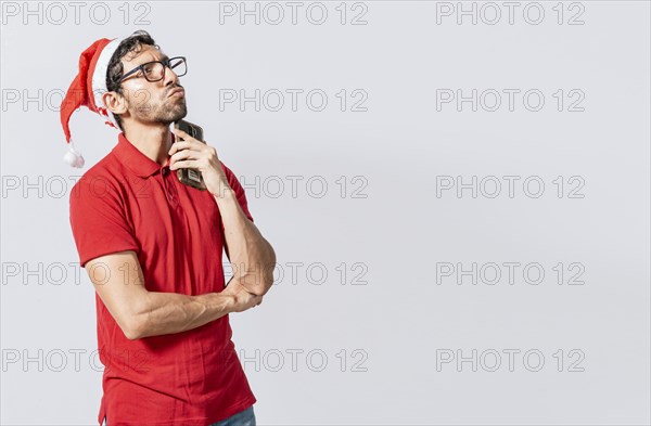 Young man in christmas clothes thoughtful with cell phone isolated