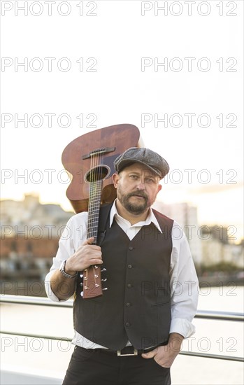 Portrait of a musician looking at camera while holding his guitar on his shoulder