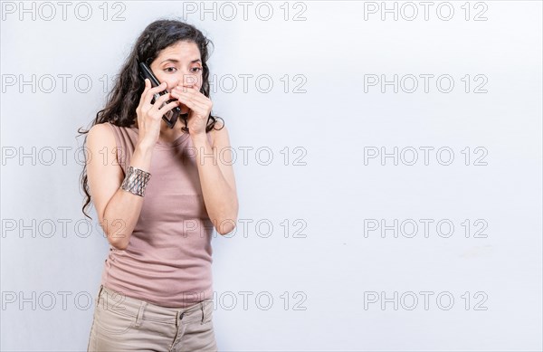 Mysterious young woman talking on the phone isolated. Woman talking secretly on the phone isolated. Latin woman talking on the phone quietly isolated