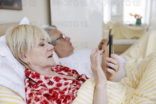 Elderly couple lying in bed together in their bedroom