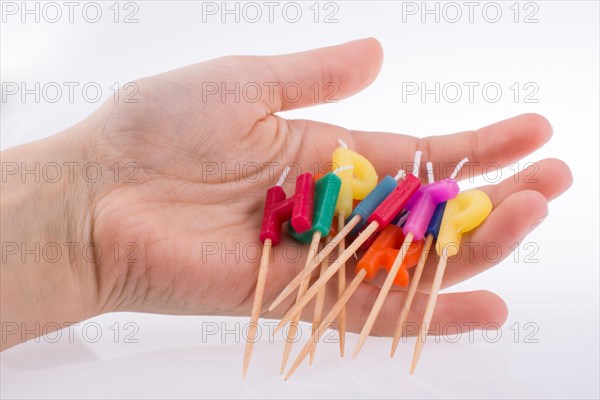 Hand holding letters made of candles on sticks