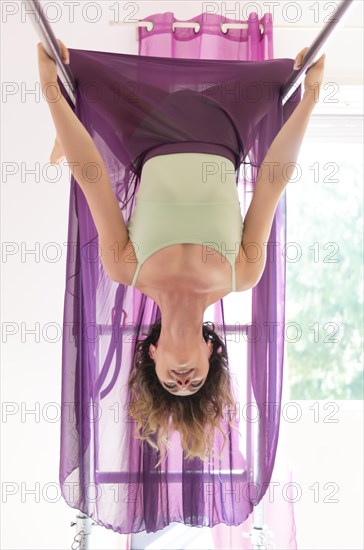 Woman Hanging Upside Down and Exercising on Pilates Machine