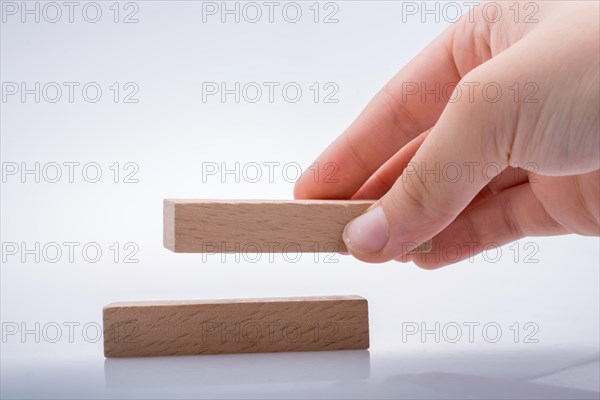 Hand holding wooden domino on a white background