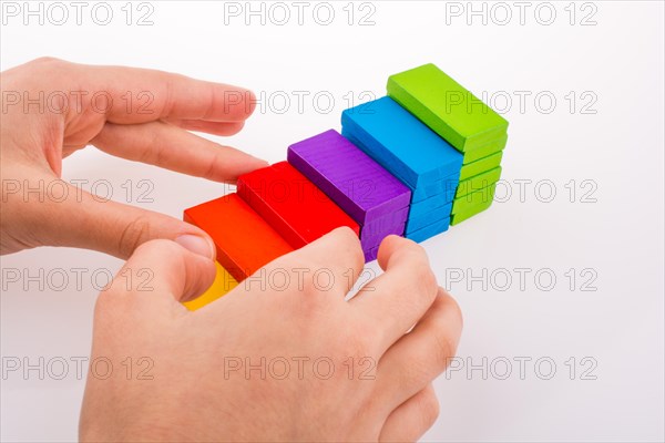 Hand playing with colored domino on white background