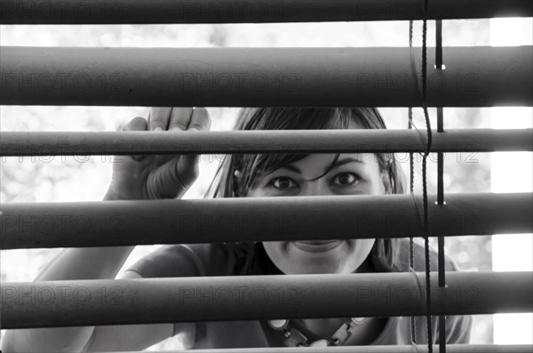 Woman Watching Out Through Window Blinds
