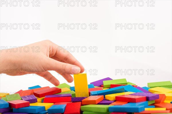 Hand playing with colored domino on white background