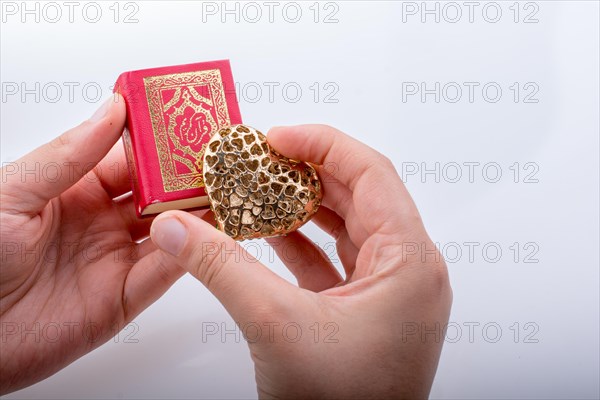 Hand holding Heart shape and Islamic Holy Book Quran