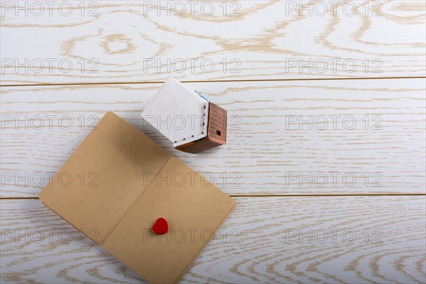 Little model house and a notebook on a parquet background