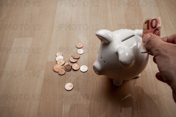 Male hand puts 10 euro note into piggy bank