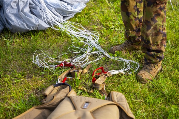 Military Parachuter Standing on the Grass with His Parachute in Switzerland