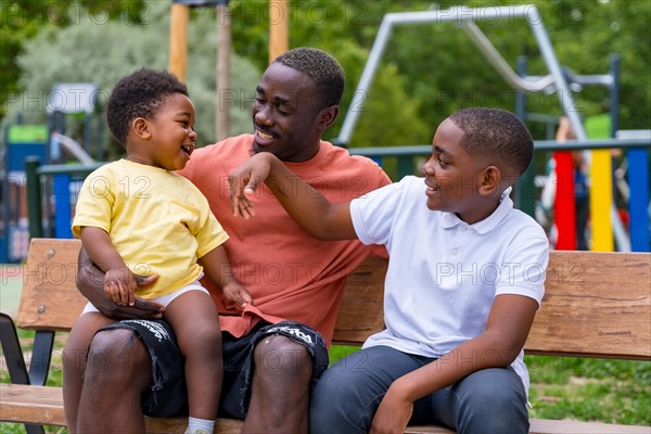 African black ethnicity father having fun with his children in playground of city park